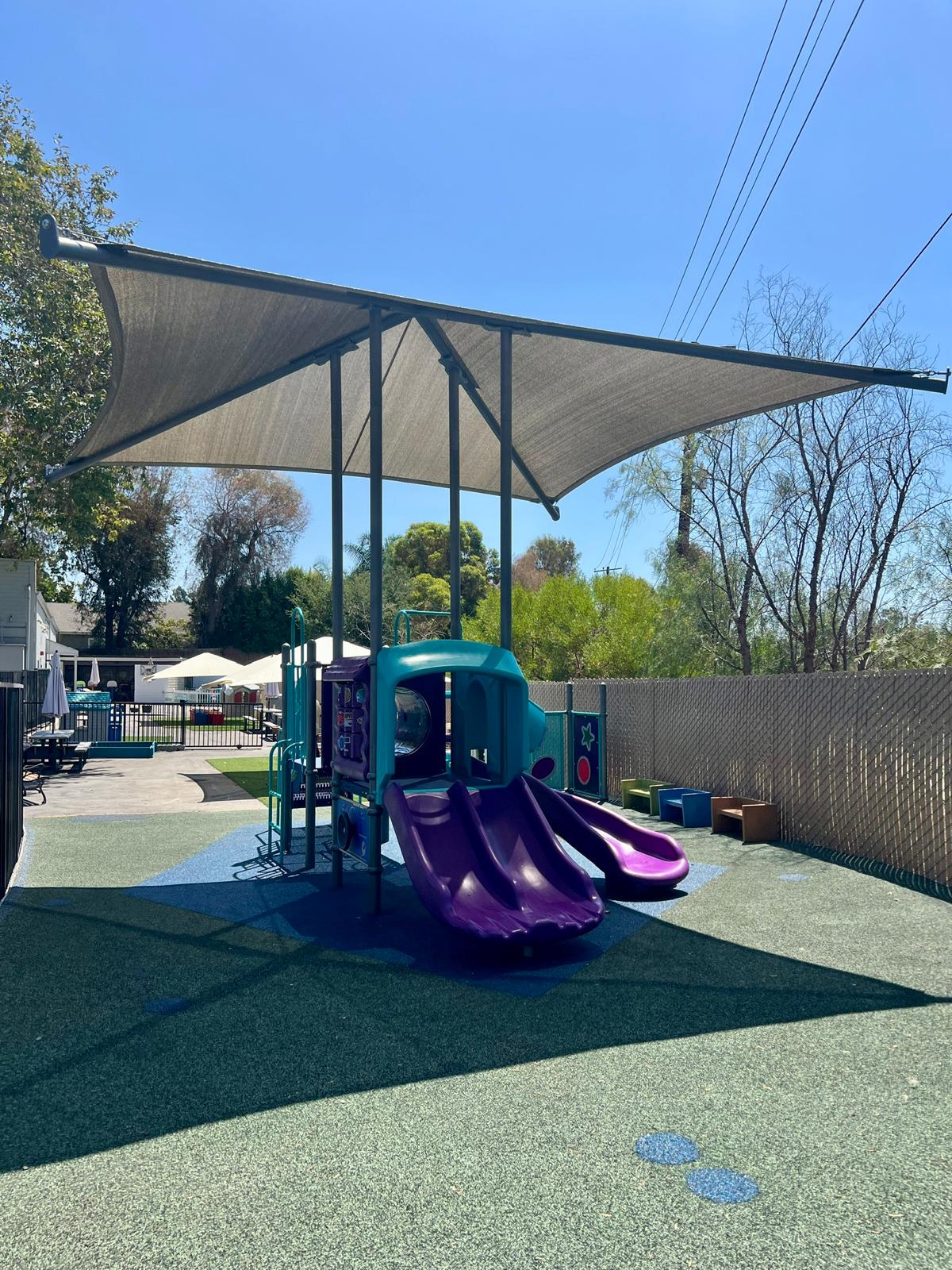 Shaded outdoor playground with slides at Happy Minds Kids Academy