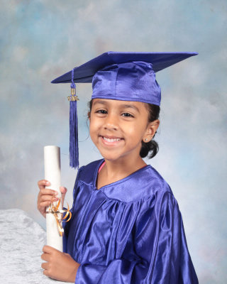 Preschool graduate in a cap and gown holding a diploma